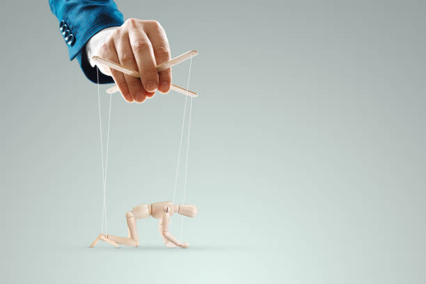 istock Male hand, puppeteer controls the puppet puppet with strings. A doll on her knees. The concept of world conspiracy, world government, manipulation, control. 1330673462