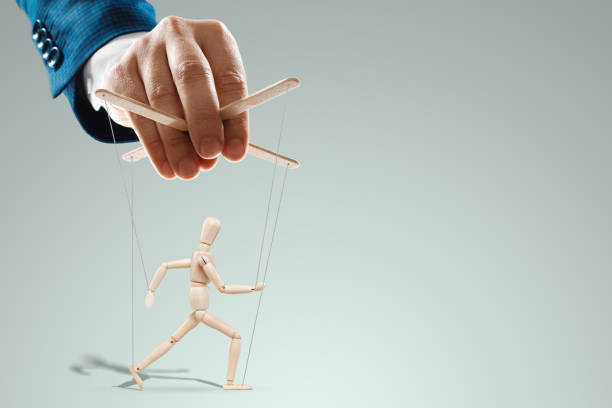 istock Male hand, puppeteer controls the puppet puppet with strings. A doll on her knees. The concept of world conspiracy, world government, manipulation, control. 1330673480