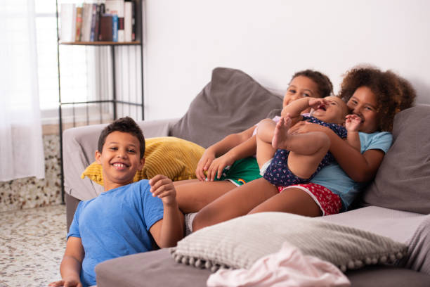 Friendly family, best friends! Children with the baby having fun, sitting on a sofa at home. 6 9 months stock pictures, royalty-free photos & images