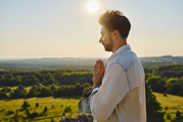 istock Young man prying outdoors in the mountains during sunny summer day 1330674329