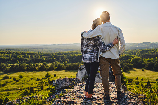 young couple enjoying the view standing together during sunny summer hike