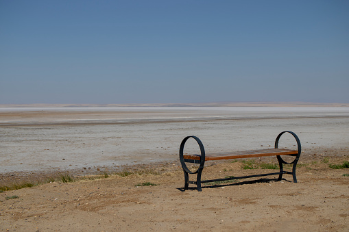 Empty bench standing towards the horizon in the deep white and great void of the salt lake. solitude and peace