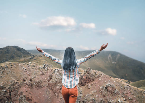 istock Woman standing with raised arms in the mountains. 1330679868