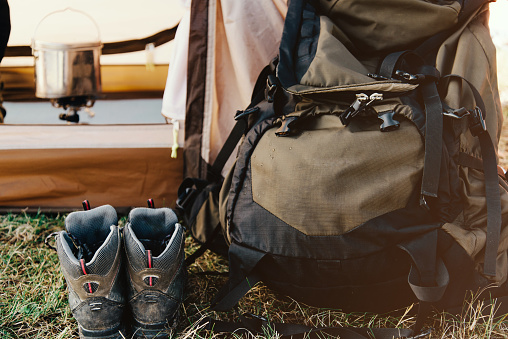 Close-up of hiking backpack and trekking boots against the background of a tourist tent.