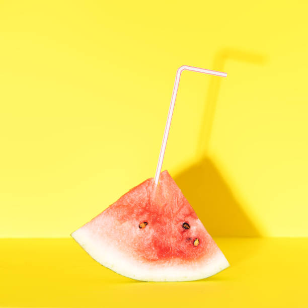 istock Straw is inserted into piece of ripe watermelon against yellow background 1330683122