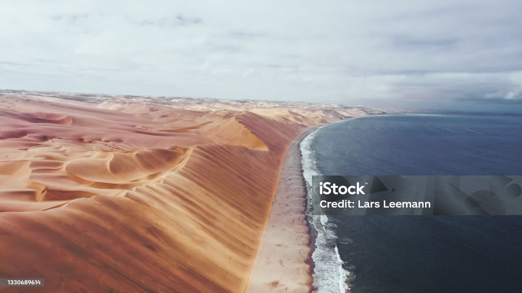 Sandwich Harbour Namib Naukluft National Park Namibia large mighty sand dunes stretch out over the ice-cold atlantic sea Namib Desert Stock Photo