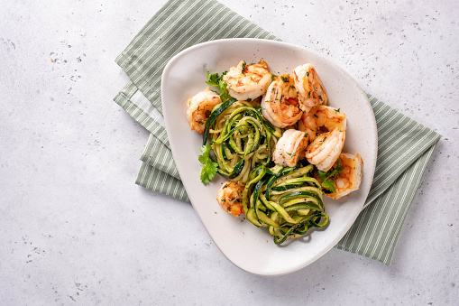 zucchini pasta with shrimps on white plate