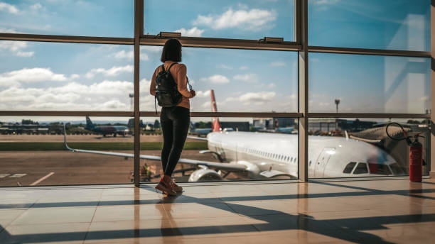 Rear view of female at airport. Photo of happy traveler waiting for the flight in airport, departure terminal, immigration concept airport terminal stock pictures, royalty-free photos & images