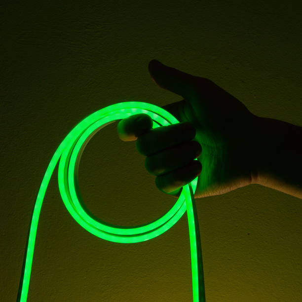 istock Flexible green led tape neon in hand on black background 1330692718