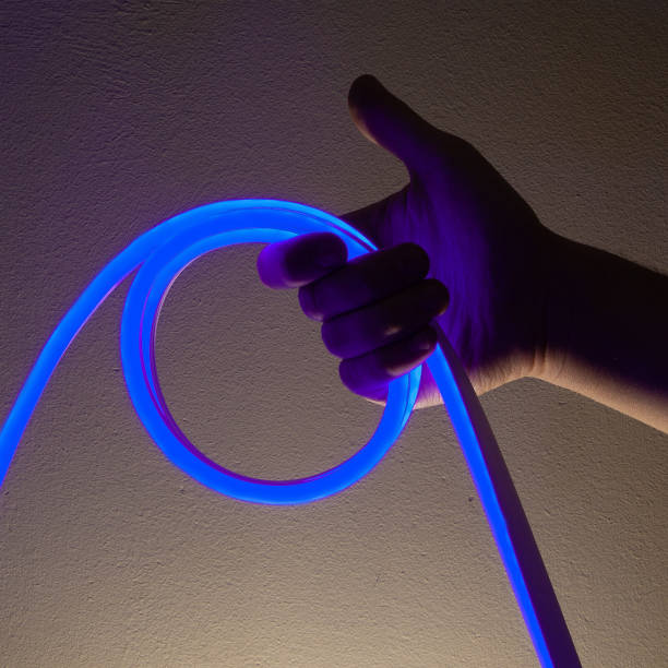 istock Flexible blue led tape neon in hand on black background 1330692761