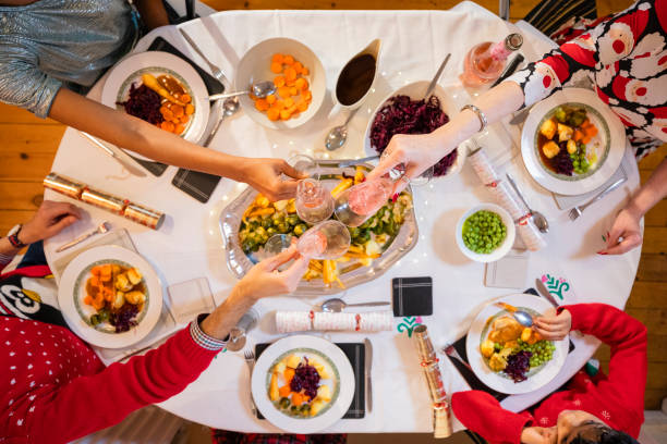 Family Ready to Eat Christmas Dinner Directly above shot of a family sitting at a dining table on Christmas Day. They are having a vegan lunch with vegetables and a roasted sprout stalk. They are toasting their drinks on Christmas day. happy green peas stock pictures, royalty-free photos & images