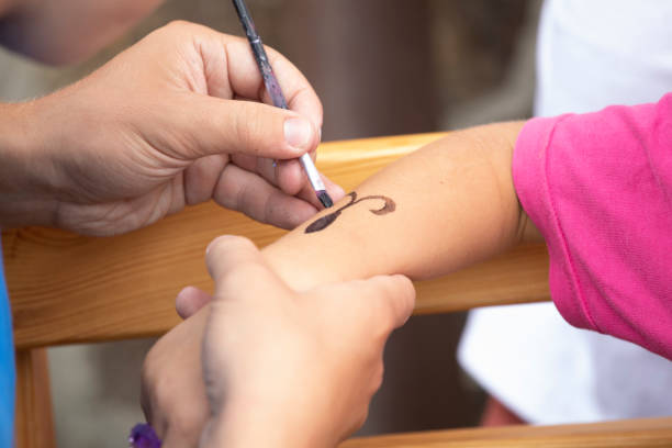 dad draw with brush black pattern on children's hand, kids party