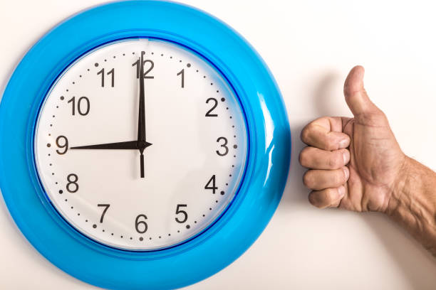 orologio con frecce e la mano dell'uomo mostra pollice in su. - clock time clock hand urgency foto e immagini stock