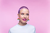 Headshot of woman with short purple hair and rainbow earrings