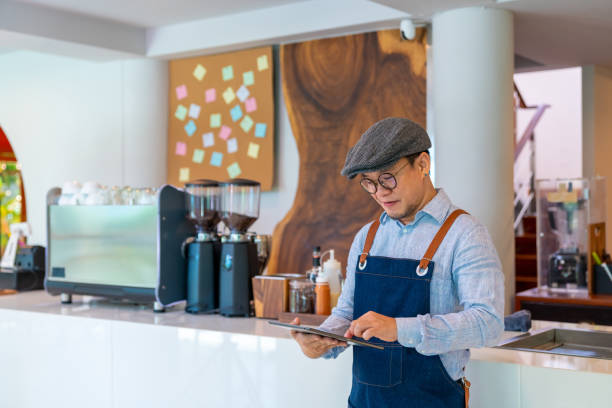 istock Asian man coffee shop owner checking inventory on digital tablet 1330699373