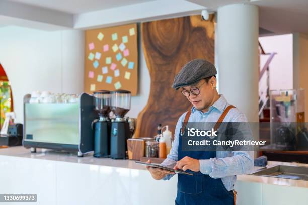 Asian Man Coffee Shop Owner Checking Inventory On Digital Tablet Stock Photo - Download Image Now