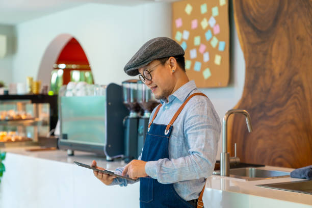 istock Asian man coffee shop owner checking inventory on digital tablet 1330699436