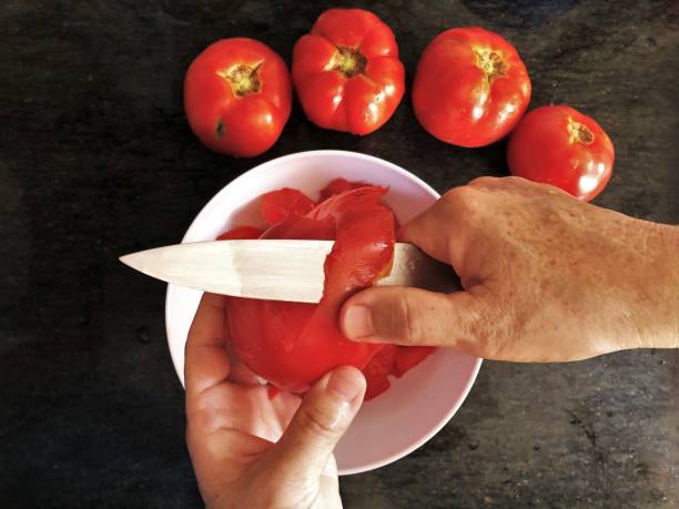 istock Senior woman hands peeling tomatoes for homemade conerva kitchen 1330700378