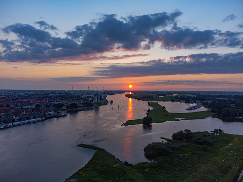 Evening on the skyline of the city of Kampen in Overijssel, The Netherlands. The sun is setting over the delta of the river IJssel in the distance. Drone point of view.