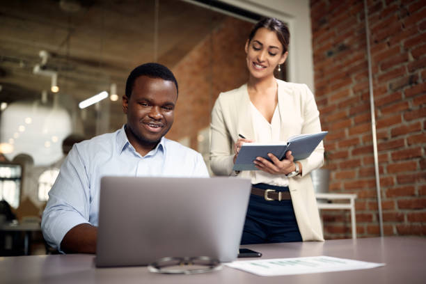 istock Happy African American businessman working on a computer while his colleague is taking notes in the office. 1330704201
