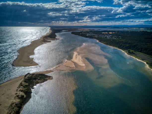 Aerial view over the mouth of the Snowy River at Marlo, Gippsland, Victoria, Australia, December 2020 The Snowy River winds 352 kilometres (219 mi) southwards from high in the mountains through inaccessible country, comprising private lands and the Snowy River National Park, eventually reaching the sea in the Snowy Inlet, at Marlo, near Orbost. The Snowy River estuary at Marlo is subject to periodic closure resulting from variations in river flows and climatic patterns. tidal inlet stock pictures, royalty-free photos & images