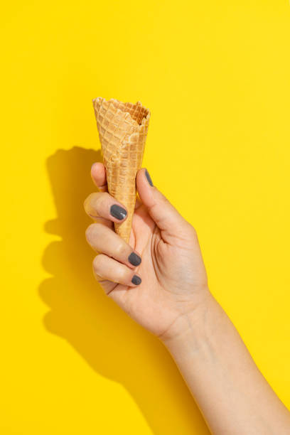 istock Hand holding empty icecream cone on yellow background 1330713800