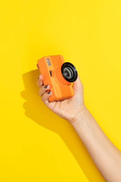 istock Hand holding camera on yellow background 1330715157