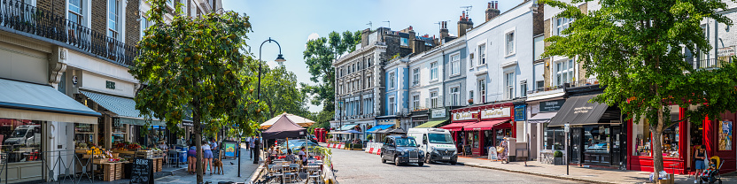 Shoppers and tourists enjoying the independent stores, restaurants and cafes in a attractive street in Primrose Hill, central London, UK.