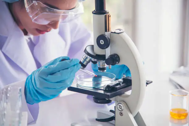 Photo of Woman scientist in lab look at science microscope medical test and research biology chemistry. Females technician laboratory analyzing scientific pharmacy genetic research. Chemistry Medical test lab