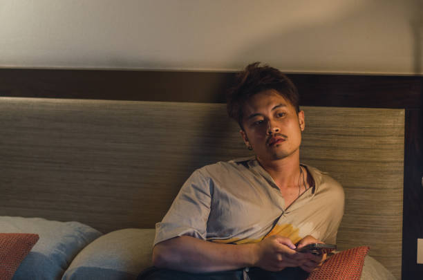 istock Young relaxed asian man traveller using smartphone in hotel room while on vacation 1330729012