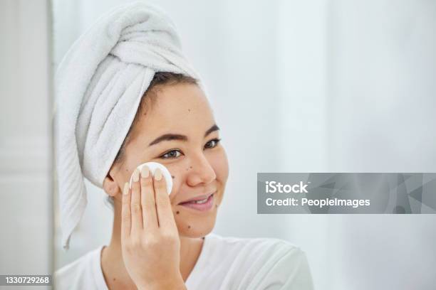 Shot Of A Young Woman Cleaning Her Face With A Cotton Pad In A Bathroom At Home Stock Photo - Download Image Now