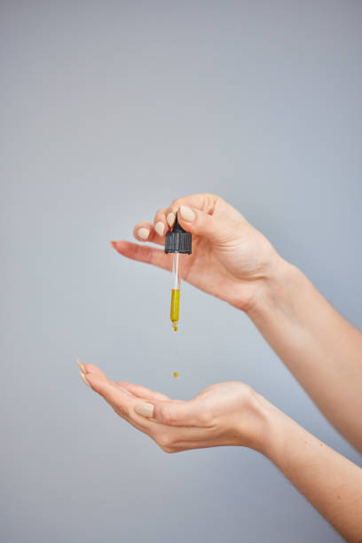 Shot of a young woman taking serum from a dropper against a grey background Just one drop does the trick medicine and science drop close up studio shot stock pictures, royalty-free photos & images