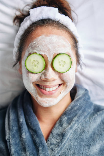 plan d’une jeune femme en s’essoupprimant avec un soin du visage de beauté - cucumber facial mask human face women photos et images de collection