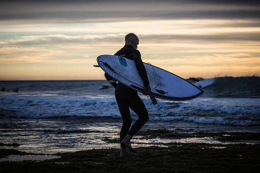 The Pacific Rim National Park on Vancouver Island on April  28, 2023:  Young male entering the water for a surfing session at Pacific Rim National Park on Vancouver Island, British Columbia