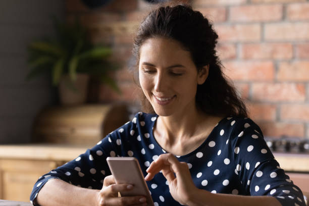 istock Happy Hispanic woman with smartphone using virtual app at home 1330730711