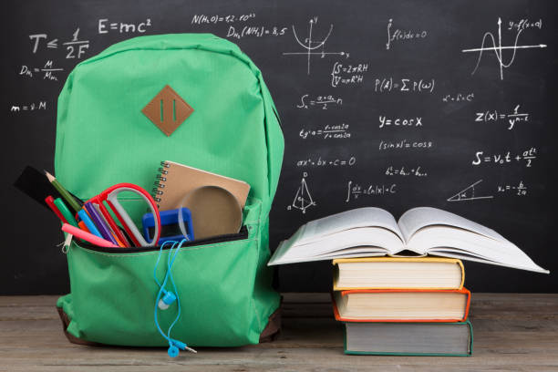 istock Education concept - school backpack with books and other supplies, blackboard background 1330730886