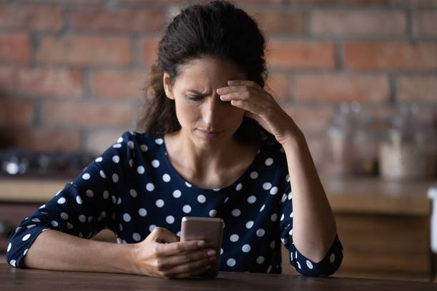 Worried Latin woman having problems with mobile phone Worried Latin woman having problems with mobile phone, using wrong working apps, getting annoyed with spam, reading message with bad news, feeling stress, angry about cellphone breakdown scammer stock pictures, royalty-free photos & images