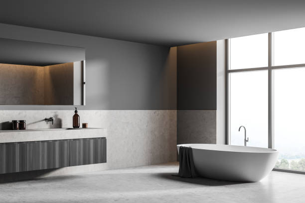 istock Bathroom interior with bathtub near window and sink with mirror, grey floor 1330731107