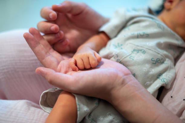 istock Mother holding newborn baby hand while cuddling on the bed 1330732378
