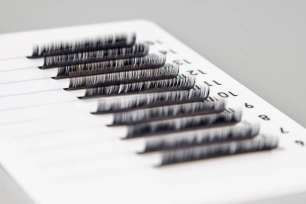 A tablet with false eyelashes on a gray background. A tablet with false eyelashes on a gray background. Cosmetic accessories for eyelash extensions clump eyelashes stock pictures, royalty-free photos & images