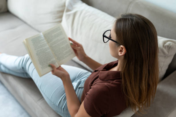 istock Young woman reading a book while relaxing at home 1330737152