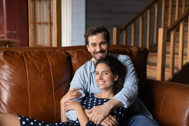 istock Happy millennial dating couple relaxing on comfortable leather couch 1330749980
