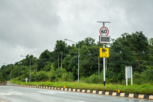 A traffic speed limit warning signpost on rural highway during the road is empty (Thai text on the sign is mean \