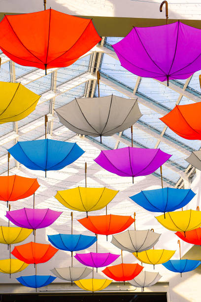 Many colorful umbrellas hanging from the ceiling under glassed roof stock photo
