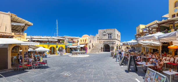 panoramic view sightseeing place at hot summer sunshine afternoon. tourists on hippocrates square at the rhodes old town main square of rhodes, greece - editorial built structure fountain town square imagens e fotografias de stock
