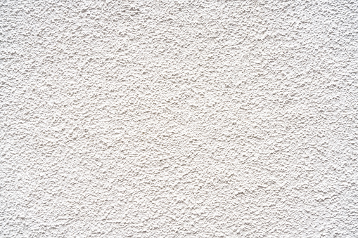 An exterior wall finished with a rough rendered surface, painted white.