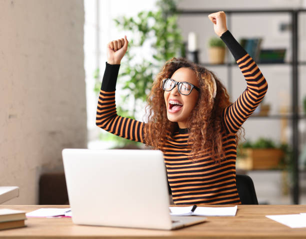 istock Overjoyed african american female  celebrating success while working remotely or studying online from home 1330757019