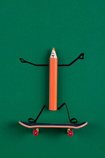 Colorful pencil on skateboard on green background