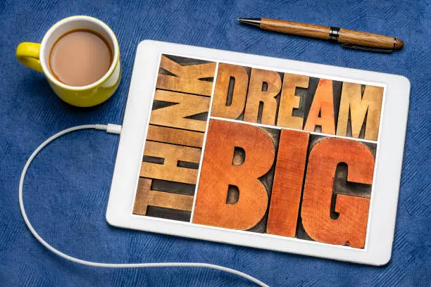 think and dream big motivational phrase -  word abstract in letterpress wood type printing blocks on a digital tablet with coffee