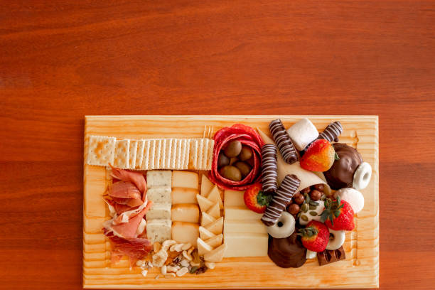 Cheese table with serrano ham, cookies, nuts, strawberries and chocolate